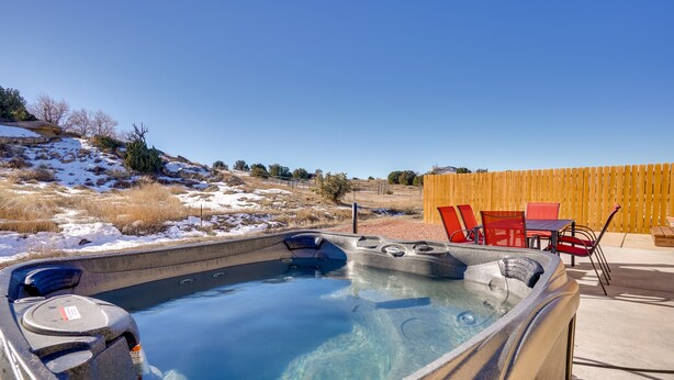 Un jacuzzi con vista despejada del paisaje circundante, incluyendo una valla de madera y un área de estar al aire libre.