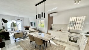 A modern kitchen with a marble countertop, a dining area with a glass-top table, and a large window providing natural light. - 6 -  Sea view apartment in Calahonda (Mijas Costa)