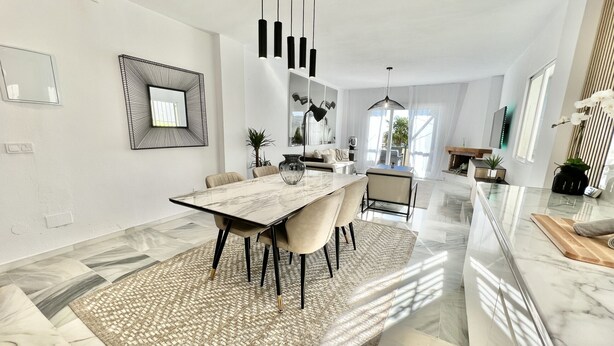 A modern dining area with a marble table, beige chairs, and a patterned rug. - 6 -  Sea view apartment in Calahonda (Mijas Costa)