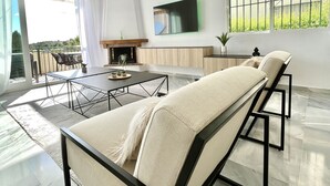A modern living room with a sofa, dining table, and TV. - 6 -  Sea view apartment in Calahonda (Mijas Costa)