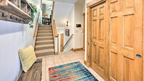 Eine Treppe mit Holzhäuschen und einem beigen Teppich, die zu einem Raum mit einer Holztür und einem farbenfrohen Teppich führt.
