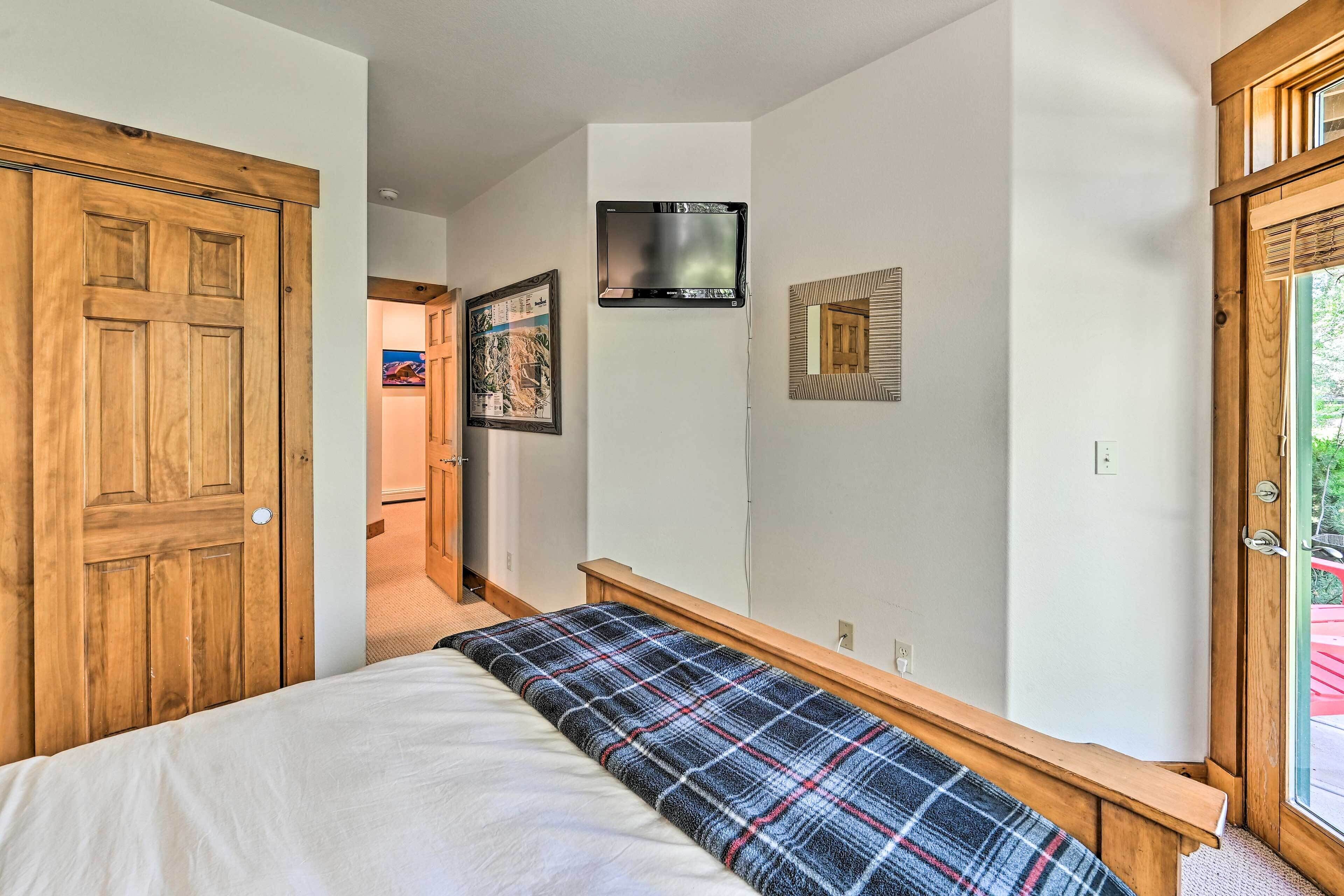 Ein Schlafzimmer mit Bett, Sitzbank, Fernseher und einer Tür.