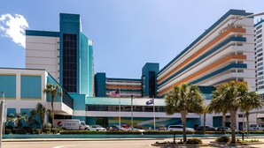 A modern hotel with a prominent 'Landmark' sign, a parking area with several cars, and a clear blue sky.