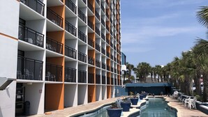 A hotel with a pool area, multiple balconies, and outdoor seating.