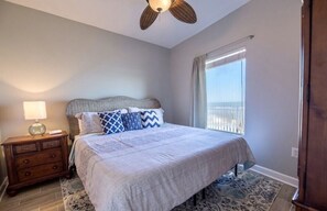 Ein Schlafzimmer mit Bett, Nachttisch, Lampe und Blick ins Freie.