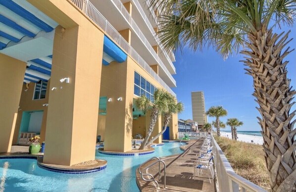 Ein Hotel mit Poolanlage, Palmen und Blick auf den Strand.