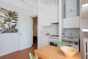 A kitchen with white cabinets, a wooden table, and a green chair.