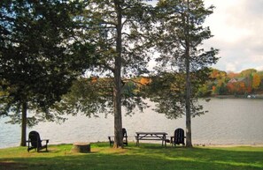 A lakeside picnic area with benches and a picnic table surrounded by trees. - Spacious Lake Community House near Hudson (Athens)