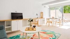 A modern living room with a flat-screen TV, a dining area with a table and chairs, and a large window offering a view of the outdoors. - Appartement Pompidou - Welkeys (La Seyne-sur-Mer)
