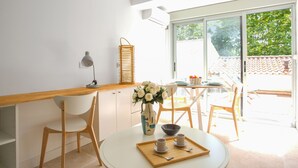 A bright kitchen with a wooden countertop, white cabinets, and a dining area with a round table and chairs. - Appartement Pompidou - Welkeys (La Seyne-sur-Mer)