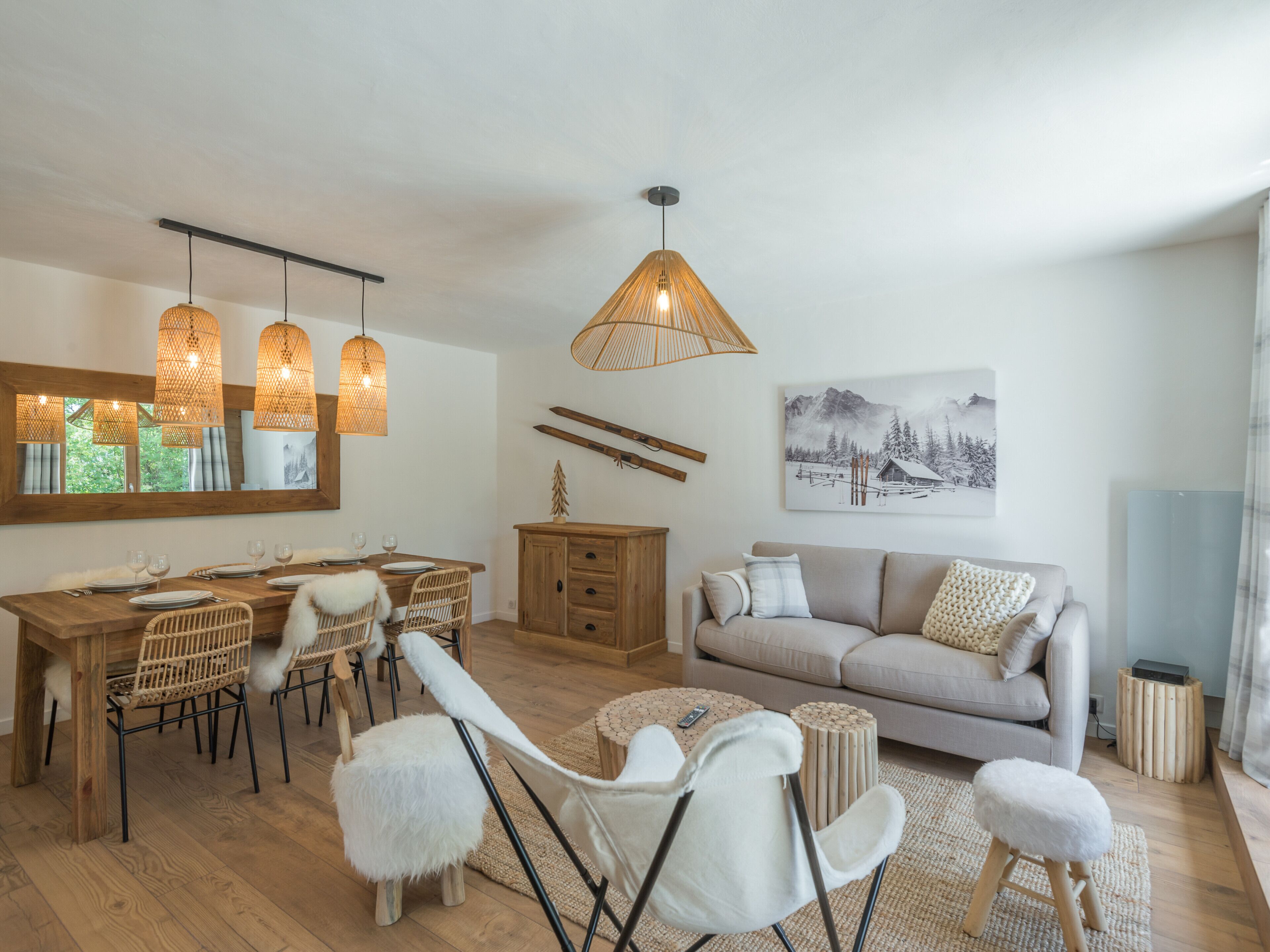 Una sala de estar moderna con una mesa de comedor de madera, sillas blancas, un sofá beige y un cuadro grande en la pared.