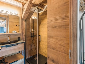 Un intérieur en bois avec une cabine de douche en verre, un miroir et un lavabo.