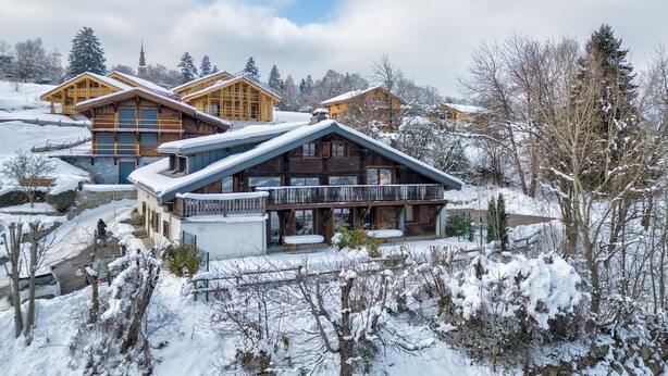 A chalet-style building with a large balcony and a covered patio area.