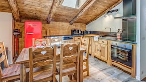 A wooden interior with a dining table, chairs, and a red refrigerator. - Appartement Alpage - Welkeys (Combloux)