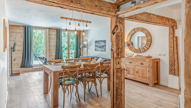 Un coin repas avec une table et des chaises en bois, un buffet en bois et un grand miroir au mur.