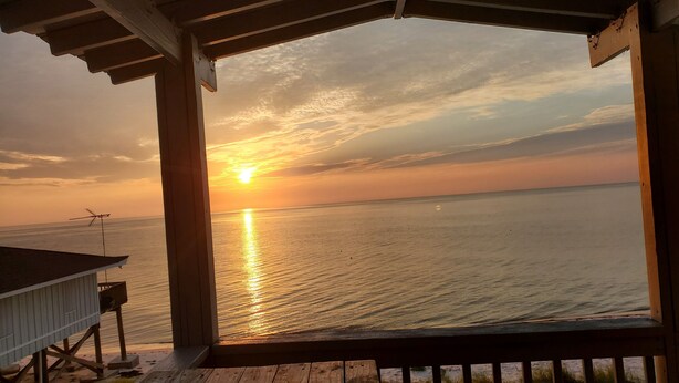 A wooden deck with a view of the sunset over the water.