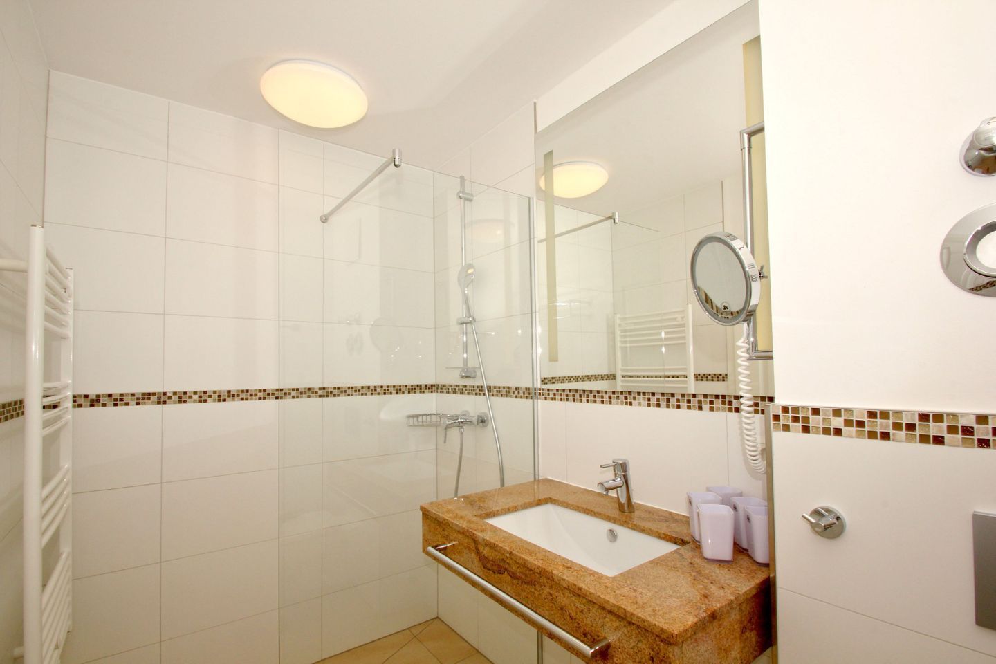 Une salle de bain équipée d’une douche, d’un lavabo, d’un miroir et d’un porte-serviettes.