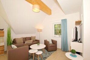 A modern living room with a sofa set, a coffee table, a TV, and a lamp.