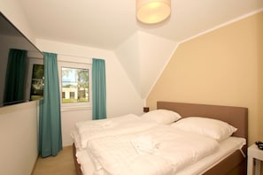 A bedroom with a bed, a nightstand, a lamp, and a window with curtains.
