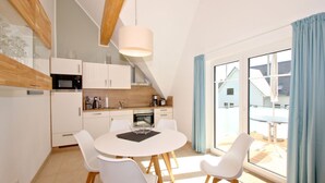 Una cucina moderna con mobili bianchi, un tavolo da pranzo con sedie bianche e un'ampia finestra con tende blu.