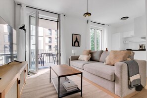 A modern living room with a sofa, a coffee table, and a view of the outside balcony.