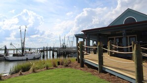 A docked boat, a wooden pier, and a building with a blue roof.