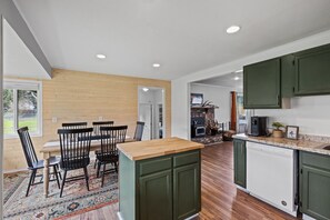 Una cocina amplia con armarios de madera, un comedor con sillas y vistas al exterior.