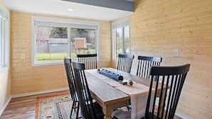 A dining area with a wooden table, four chairs, and a view of the backyard through large windows. - The Aztec Casita - Gateway to incredible memories (Forks)