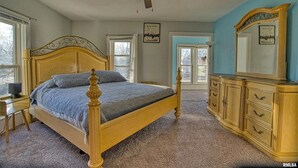 A bedroom with a wooden bed, a ceiling fan, a dresser, and a large window. - Great Rural hideaway-20 minutes from peoria (Chillicothe)