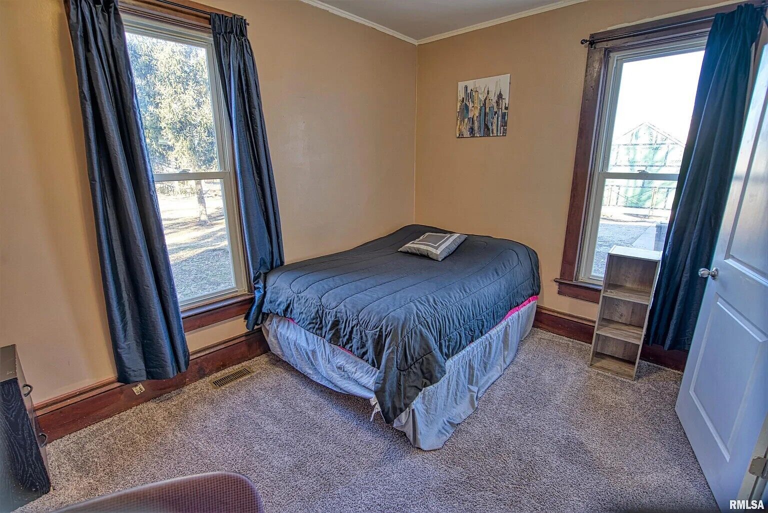 Un dormitorio con cama, ventana, puerta y un cuadro en la pared.