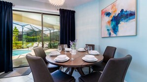 A dining area with a round table set for six, surrounded by dark chairs. - Providence Golf & Country Club Pool Home in Gated & Guarded Community (Davenport)