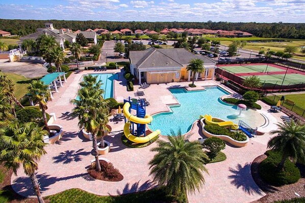 A resort with multiple swimming pools, palm trees, and a tennis court.