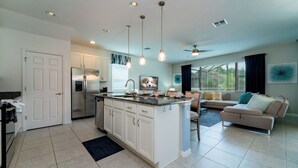 A modern kitchen with white cabinets, a central island, and pendant lighting. - Providence Golf & Country Club Pool Home in Gated & Guarded Community (Davenport)