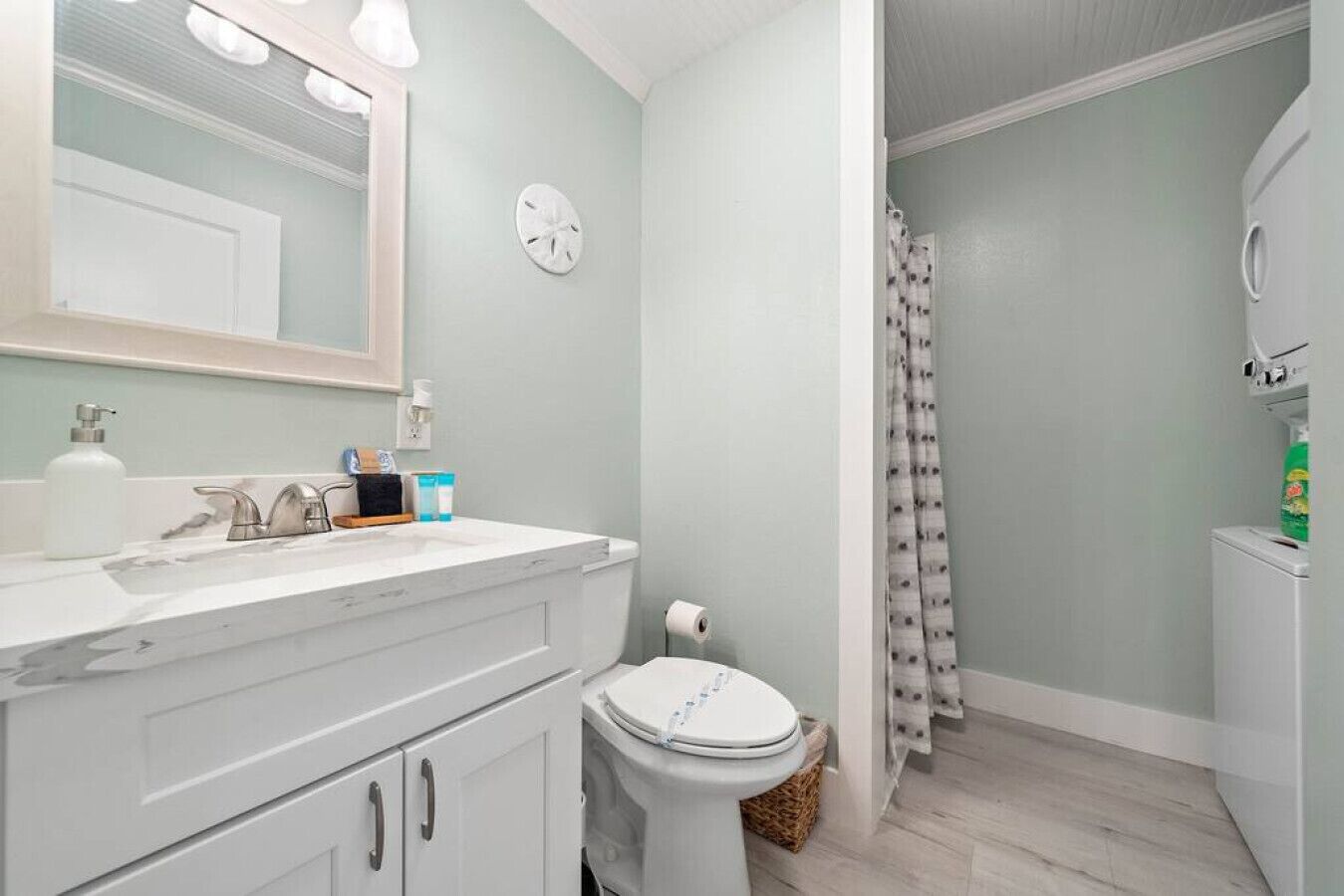 A bathroom with a white vanity, a toilet, a shower curtain, and a mirror.