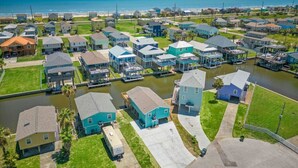 An aerial view of a residential area with houses, a canal, and a beach in the background. - Canalfront Home with Huge Deck, Close to the Beach (Galveston)