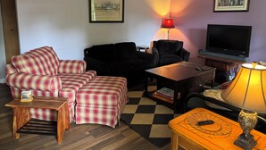 A living room with a sofa, armchair, coffee table, TV, and two lamps. - Hidden Gem 10 mins to Downtown or Wrightsville Beach. Brand New King Sized Bed (Wilmington)