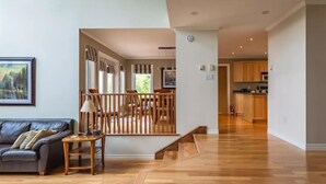A spacious living area with a wooden floor, a sofa, a lamp, and a painting on the wall.