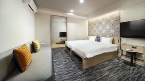 A modern hotel room with a large bed, a flat-screen TV, a small bedside table, and a wall-mounted air conditioner. - KOKO HOTEL Residence Asakusa Tawaramachi (Tokyo)