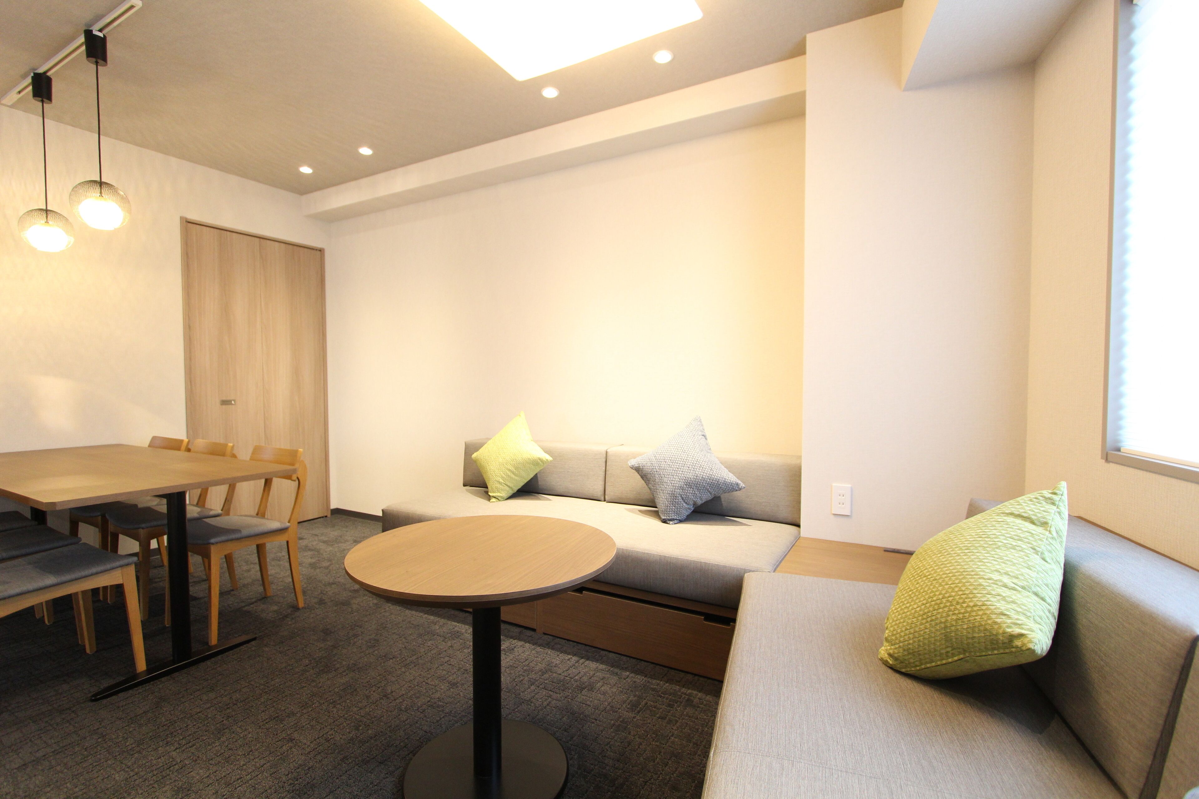 A modern room with a wooden table, chairs, a sofa, and a round table.