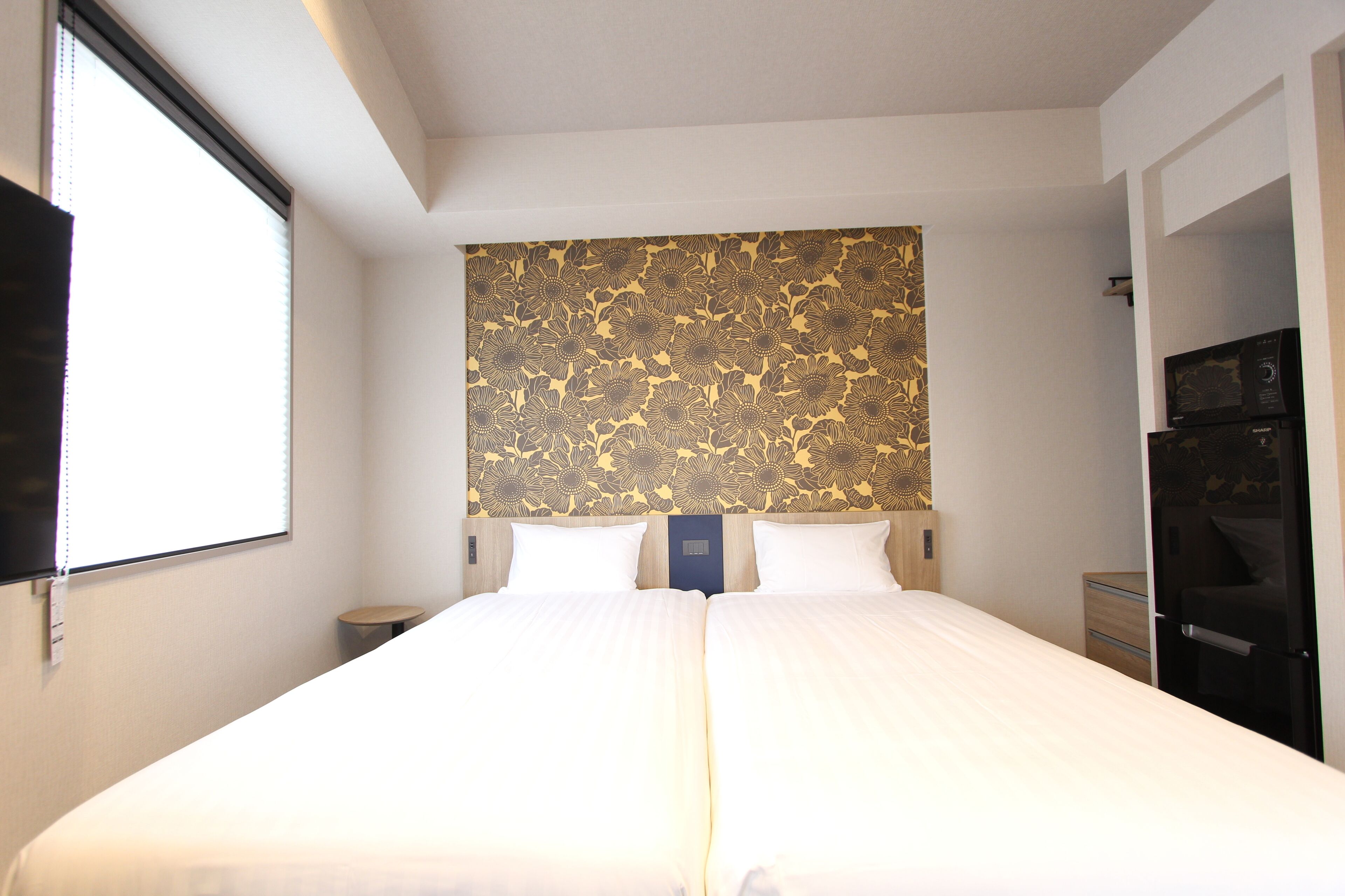 A double bed with a floral headboard, a bedside table, and a wardrobe.