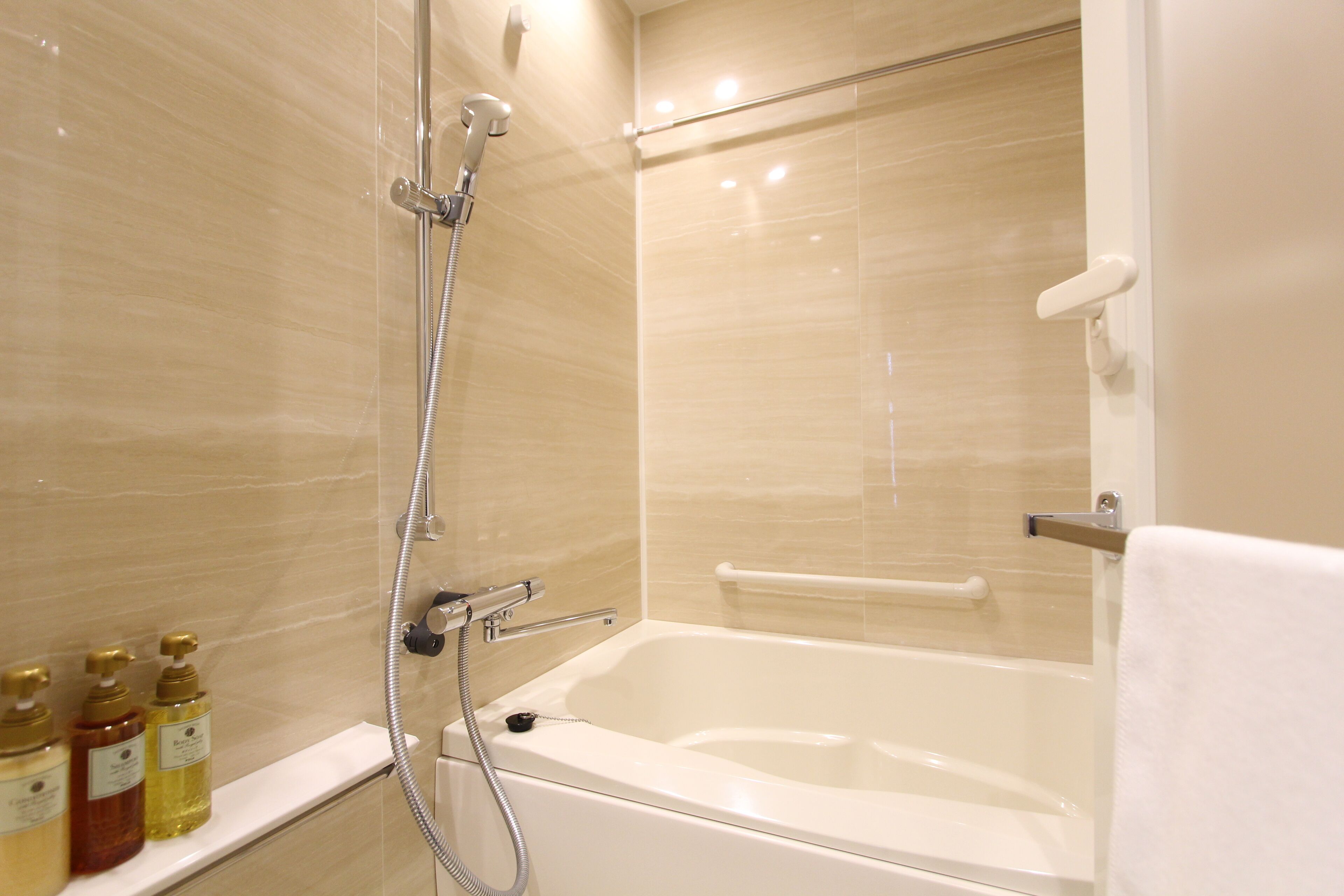 A modern bathroom with a bathtub, a shower, and a shelf with toiletries.