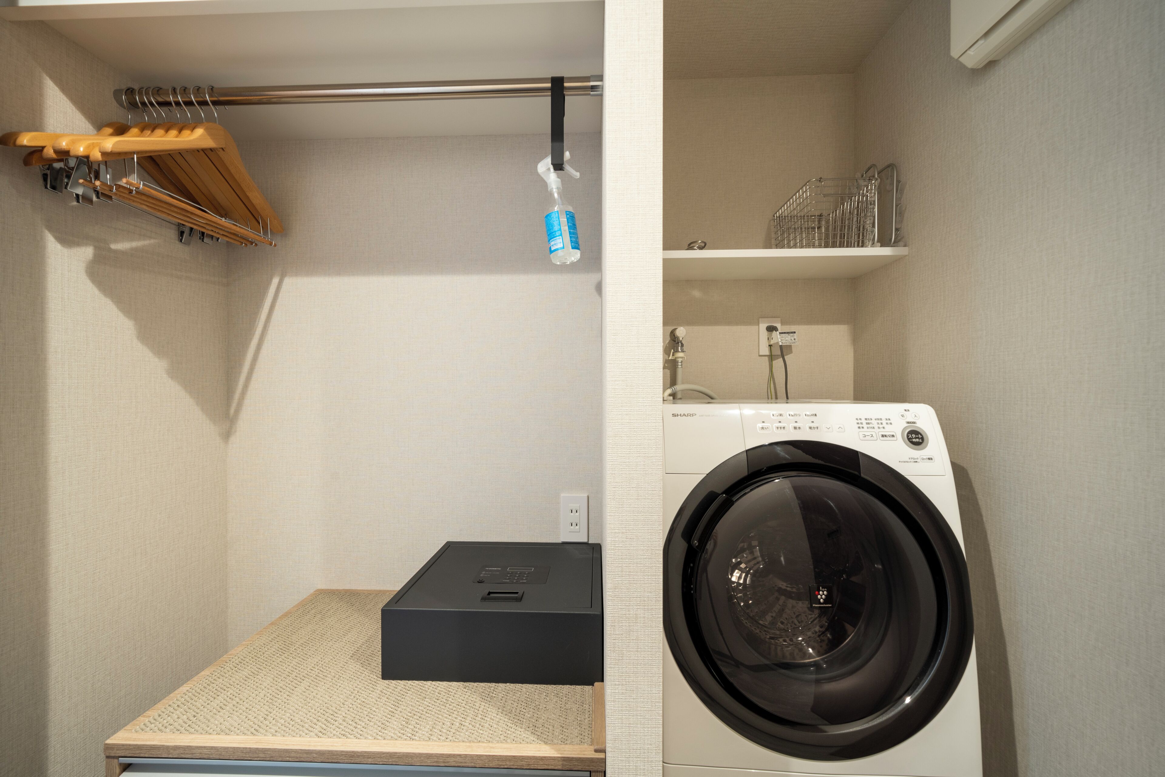 A laundry area with a washing machine, a drying rack, and a small shelf with bottles.