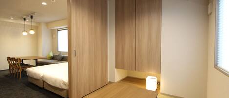 Una habitación de hotel moderna con una cama de madera, un escritorio y una silla. Hay una ventana con persianas y una lámpara en el techo.