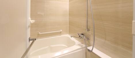 A modern bathroom with a bathtub, shower, and handrails.