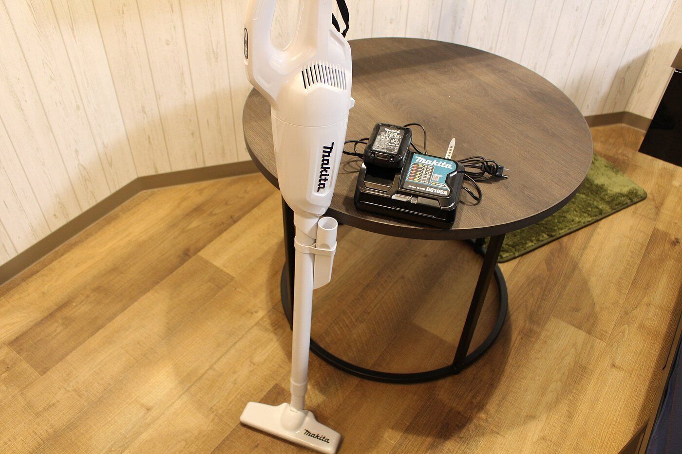 A vacuum cleaner with a power cord and a power adapter on a wooden table.