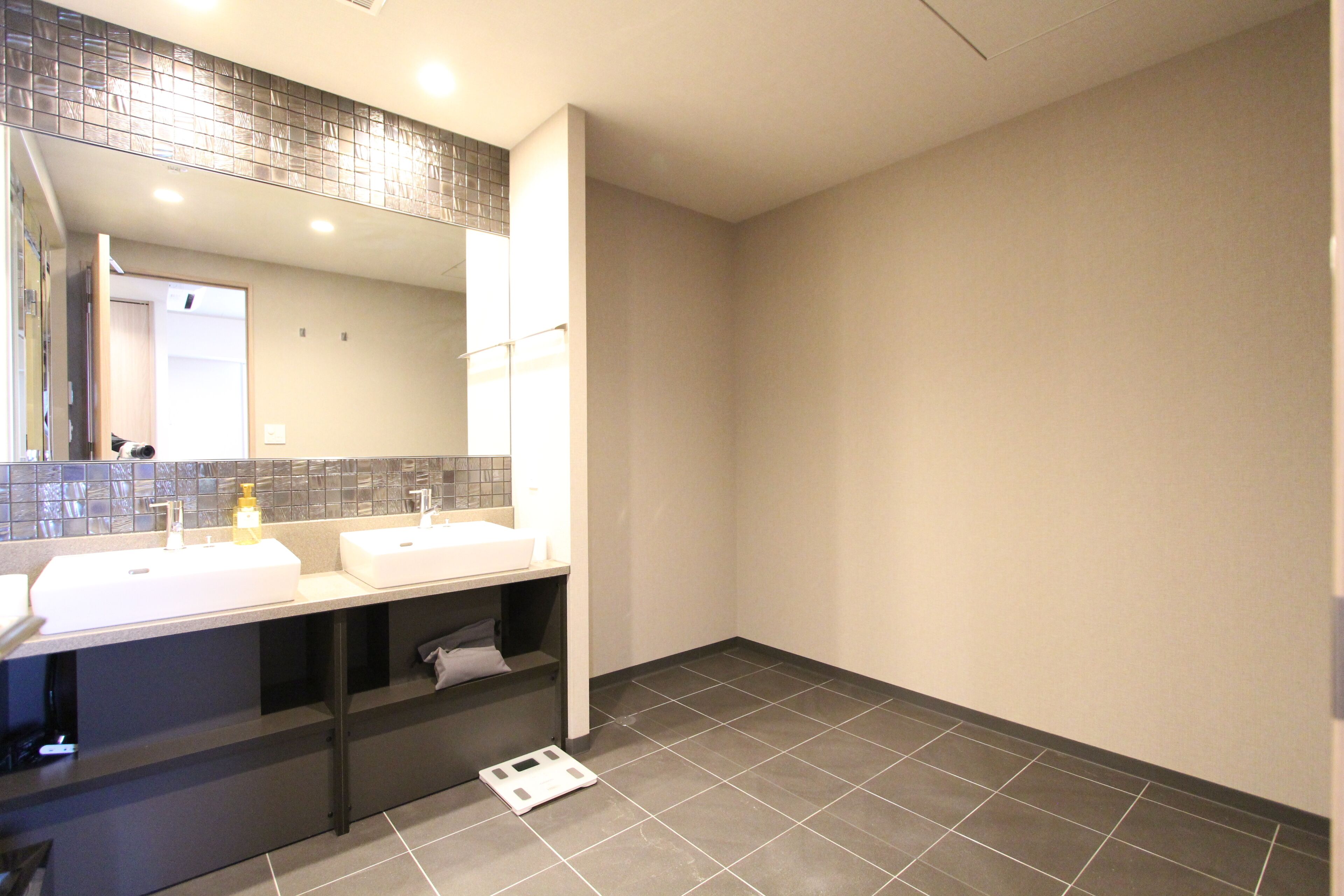 Un baño moderno con dos lavamanos, un espejo grande y suelo de baldosas.