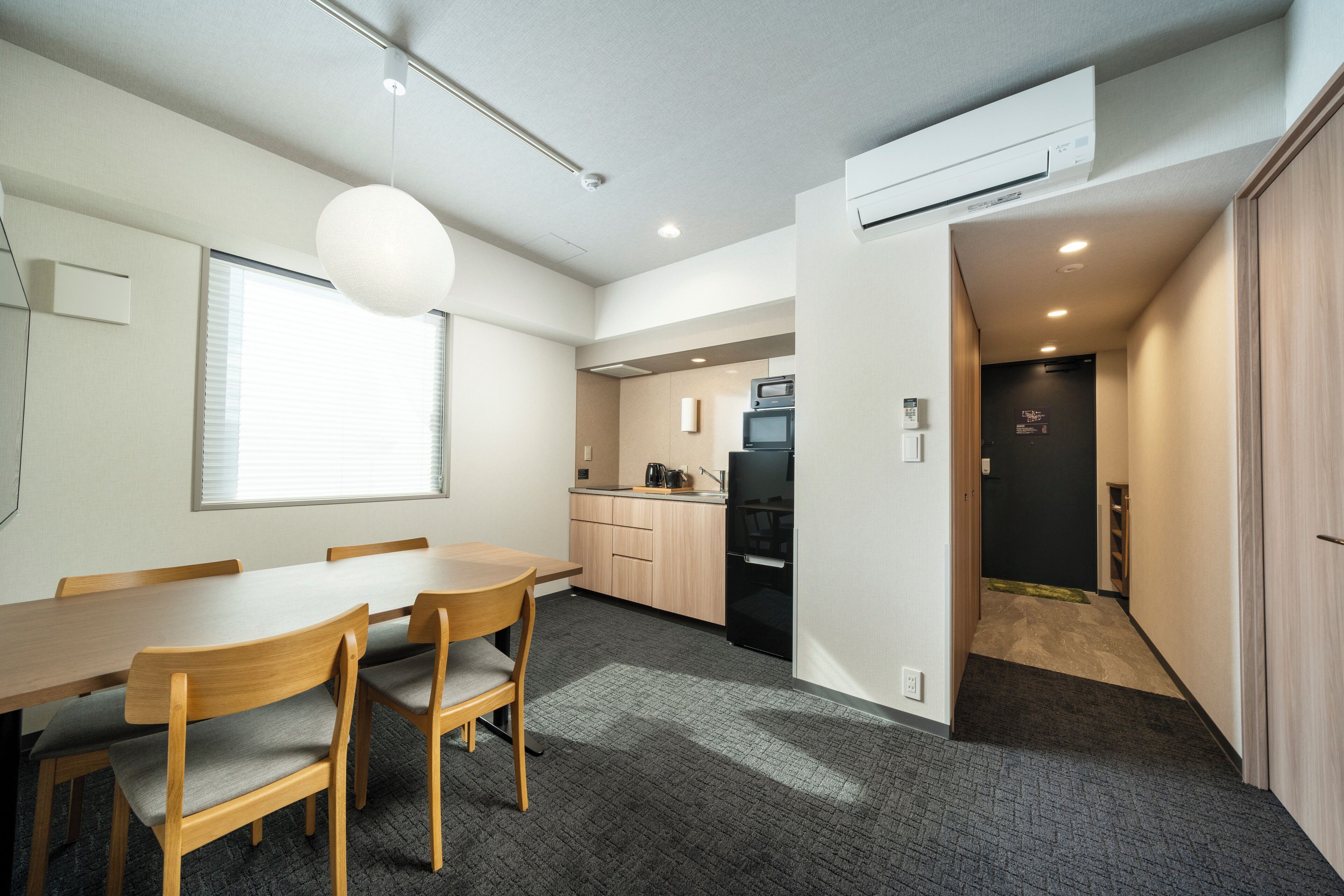 A modern kitchen with a dining area, wooden cabinets, and a built-in microwave.