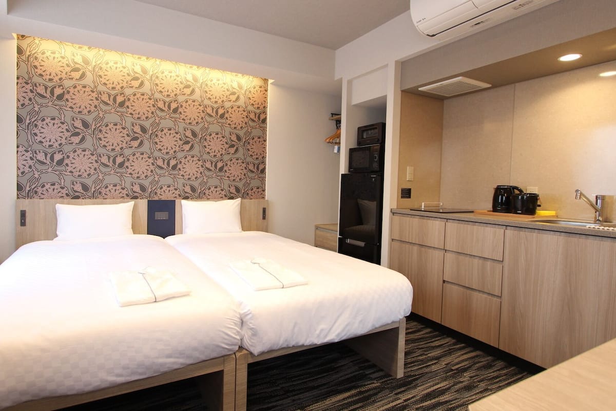 Une chambre d’hôtel comprenant un lit, un petit bureau, une kitchenette et une salle de bain.