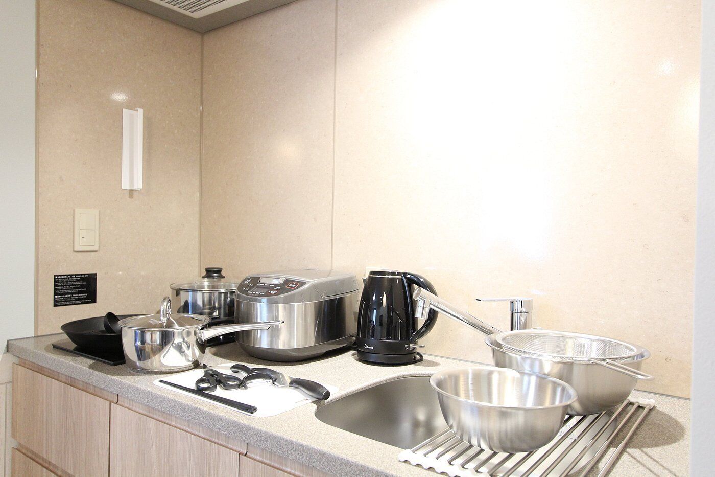 A kitchen with stainless steel appliances, including a coffee maker, pots, and a sink.