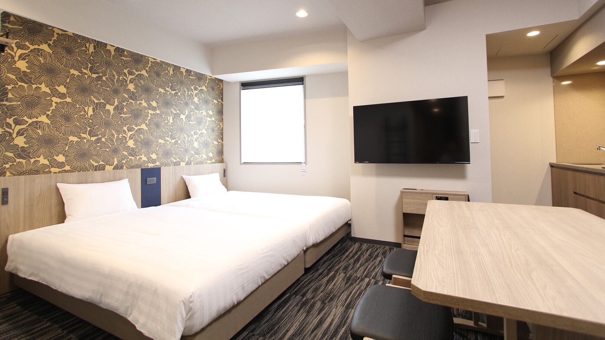 Quarto de hotel com uma cama grande, uma escrivaninha, uma televisão de tela plana e uma janela.